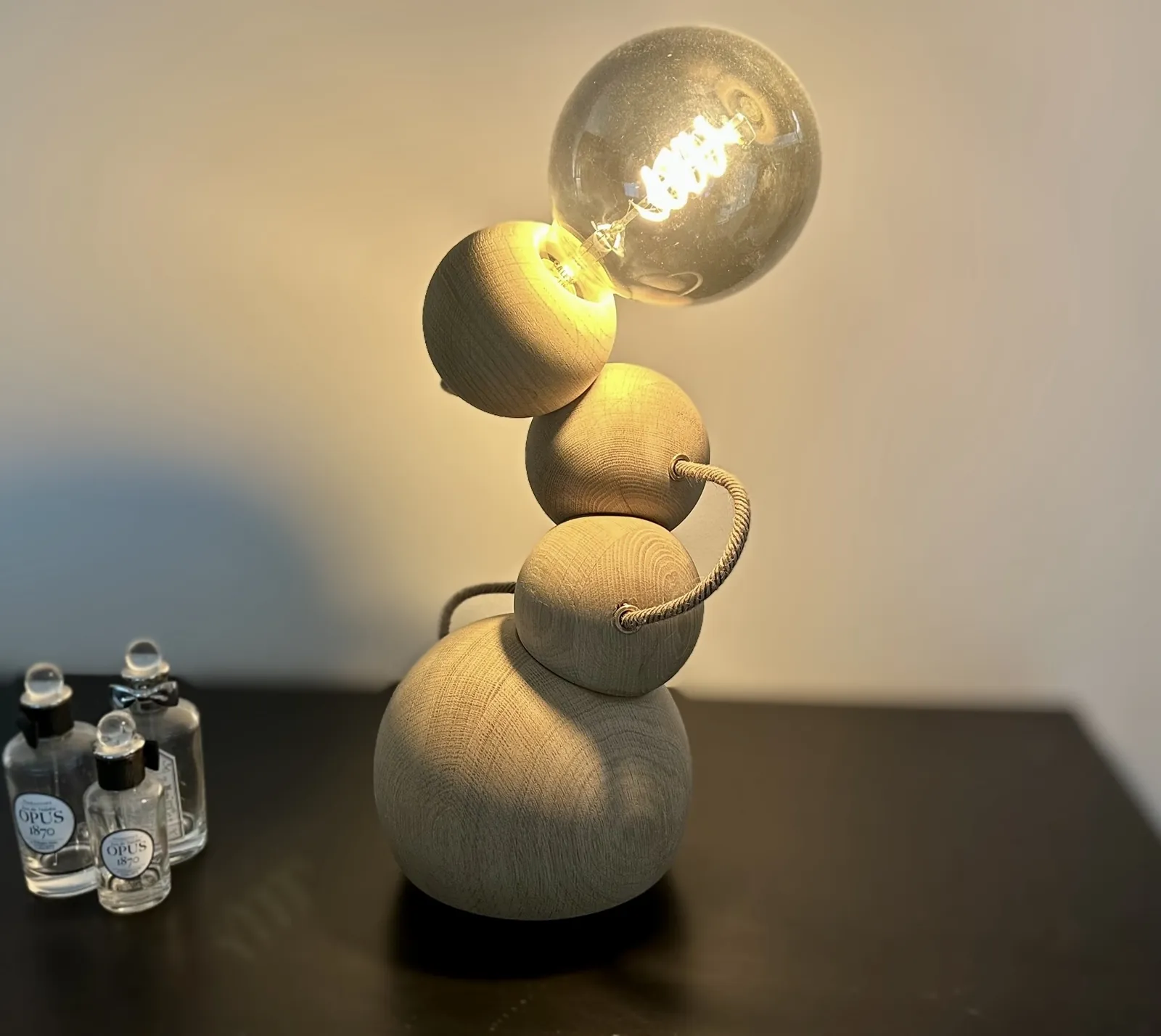 The Orbital table lamp lit, wooden spheres glowing on a dark table