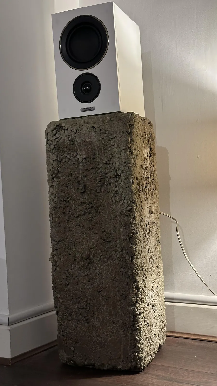 The Urban plinth beside a wall, a white speaker on top